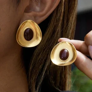 Close-up of 18K gold enamel earrings being worn, model wearing earring on ear with one held in hand, demonstrating waterproof hypoallergenic quality