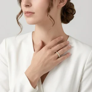 Woman wearing 18K gold eternity ring on finger close-up studio shot white blazer