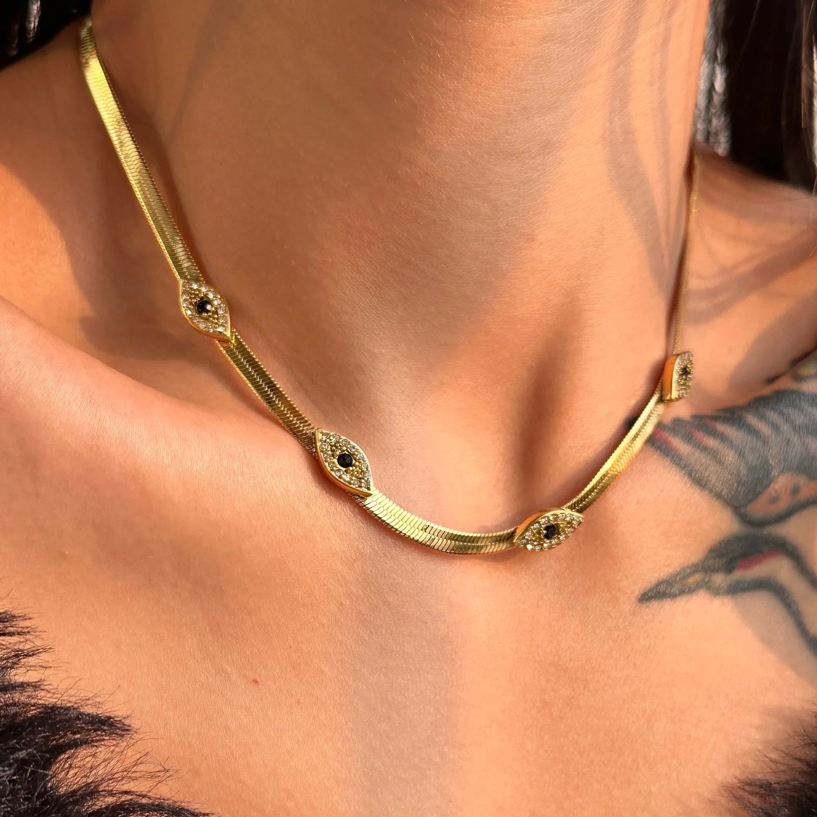 18K gold evil eye herringbone necklace side profile view on model showing fitted chain with evil eye motifs at collarbone