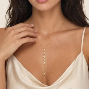 18k gold clover charm drop necklace worn on female model champagne satin camisole collarbone close-up
