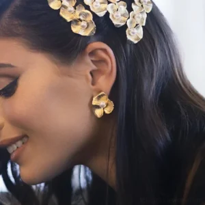 woman wearing 18K gold floral pearl stud earrings on earlobe close-up side profile view with dark long hair and floral hair accessory styling inspiration