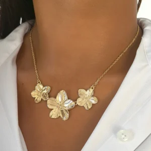 18K gold flower necklace worn on model at collarbone, three textured flower charms in brushed gold finish, styling on white collared shirt