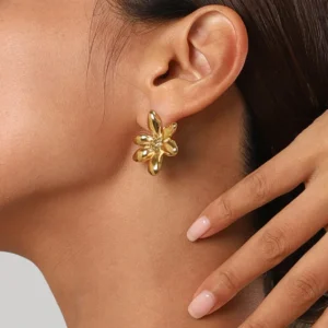 Golden 18K gold flower stud earrings worn on female model's earlobe, close-up side profile showing secure fit and metallic shine
