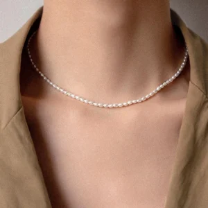 Delicate freshwater pearl choker worn on model neck with tan blazer - minimal 18K gold plated pearl necklace close-up detail