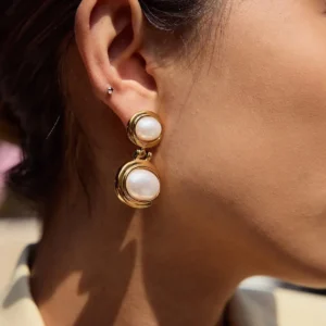Close-up side view of 18K gold pearl earrings worn on female model ear demonstrating elegant drop style and pearl luster