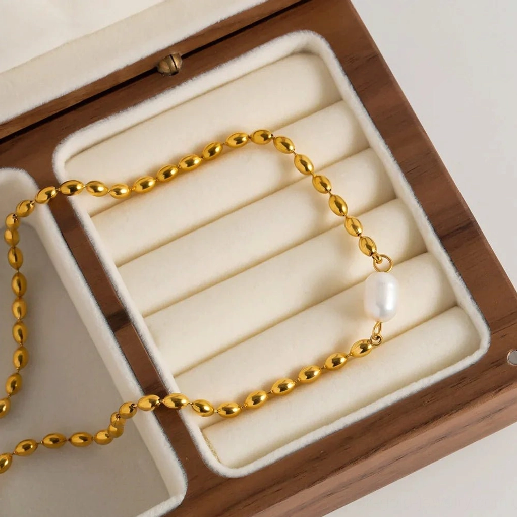 18K gold freshwater pearl necklace neatly arranged on velvet jewelry tray - overhead detail view of craftsmanship