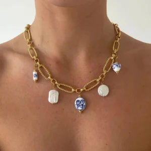 18K gold necklace worn on female model's neck and collarbone showcasing dual layered chains with mixed dangling pearl and porcelain pendant accents close-up