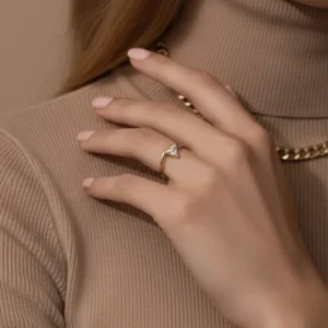 Close-up detail of trillion-cut diamond 18K gold ring worn on middle finger, showing polished gold finish and stone brilliance