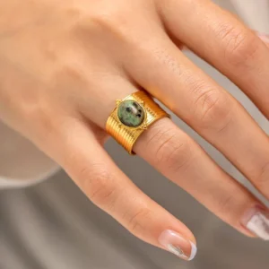 Green gemstone 18K gold adjustable ring worn on woman's hand with neutral manicure, close-up detail view