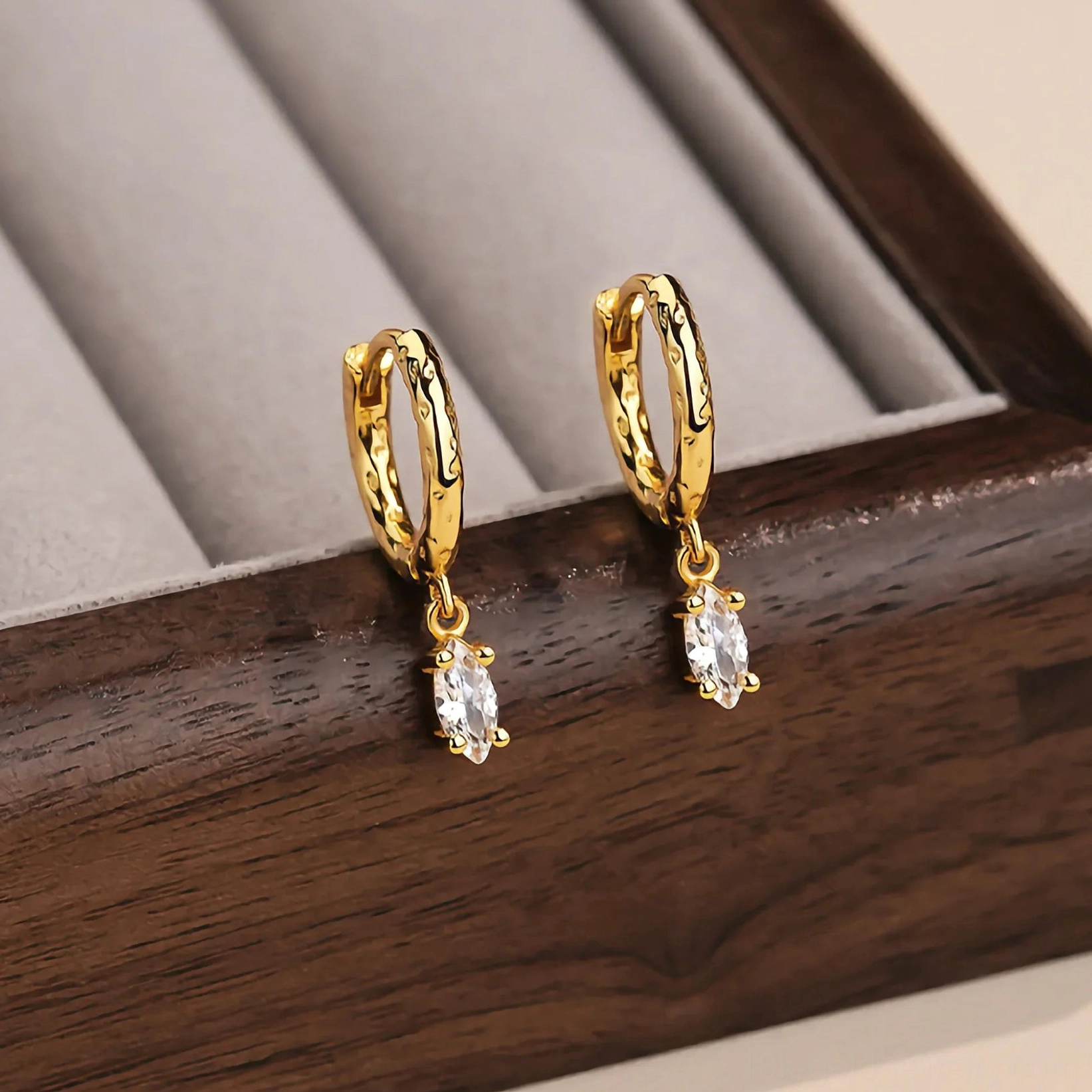 Pair of 18K gold hammered diamond drop hoop earrings displayed on velvet jewelry tray showing full product with sparkling CZ pendants