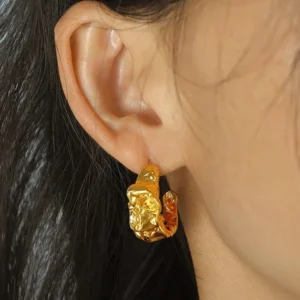 Woman wearing chunky 18K gold textured hoop earrings, close-up ear view showcasing wrinkled hammered surface detail