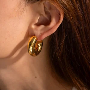 18K gold hammered hoop earrings worn on ear close-up side view showing textured surface and warm gold tone on model