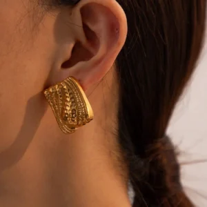 Gold hammered wavy stud earrings worn on ear with braided hair model showcasing fit