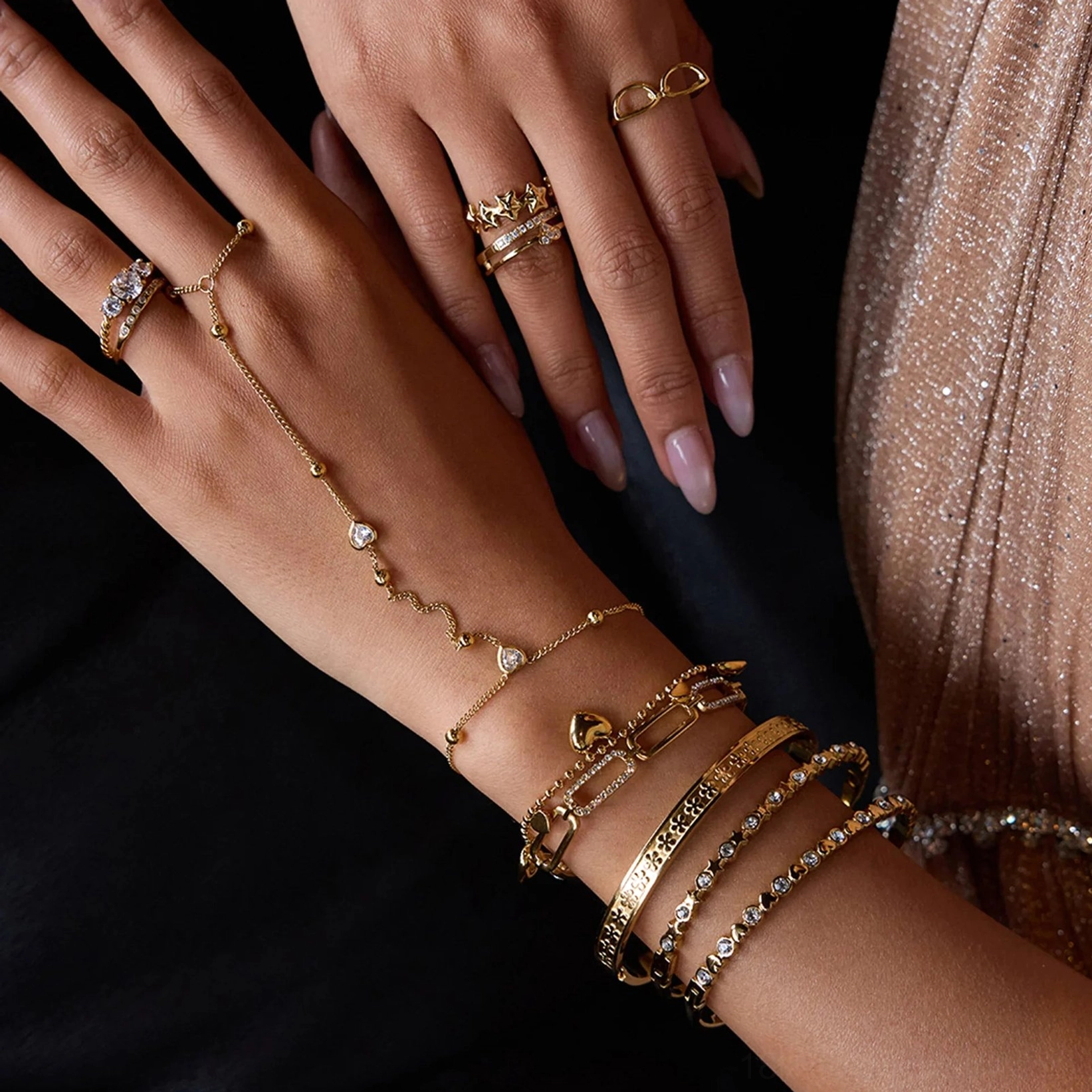 Beaded 18K gold hand chain paired with stackable bracelets and rings on female model in party outfit, hand jewelry combination