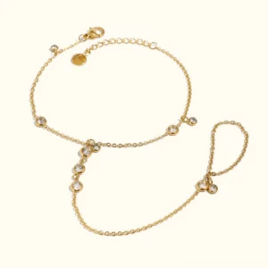 18K gold hand chain bracelet with bezel-set CZ diamond accents on light beige background, flat lay overhead view