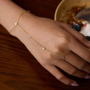 18K gold hand chain worn on model's hand, close-up side view showing delicate chain links and sparkling CZ diamond details