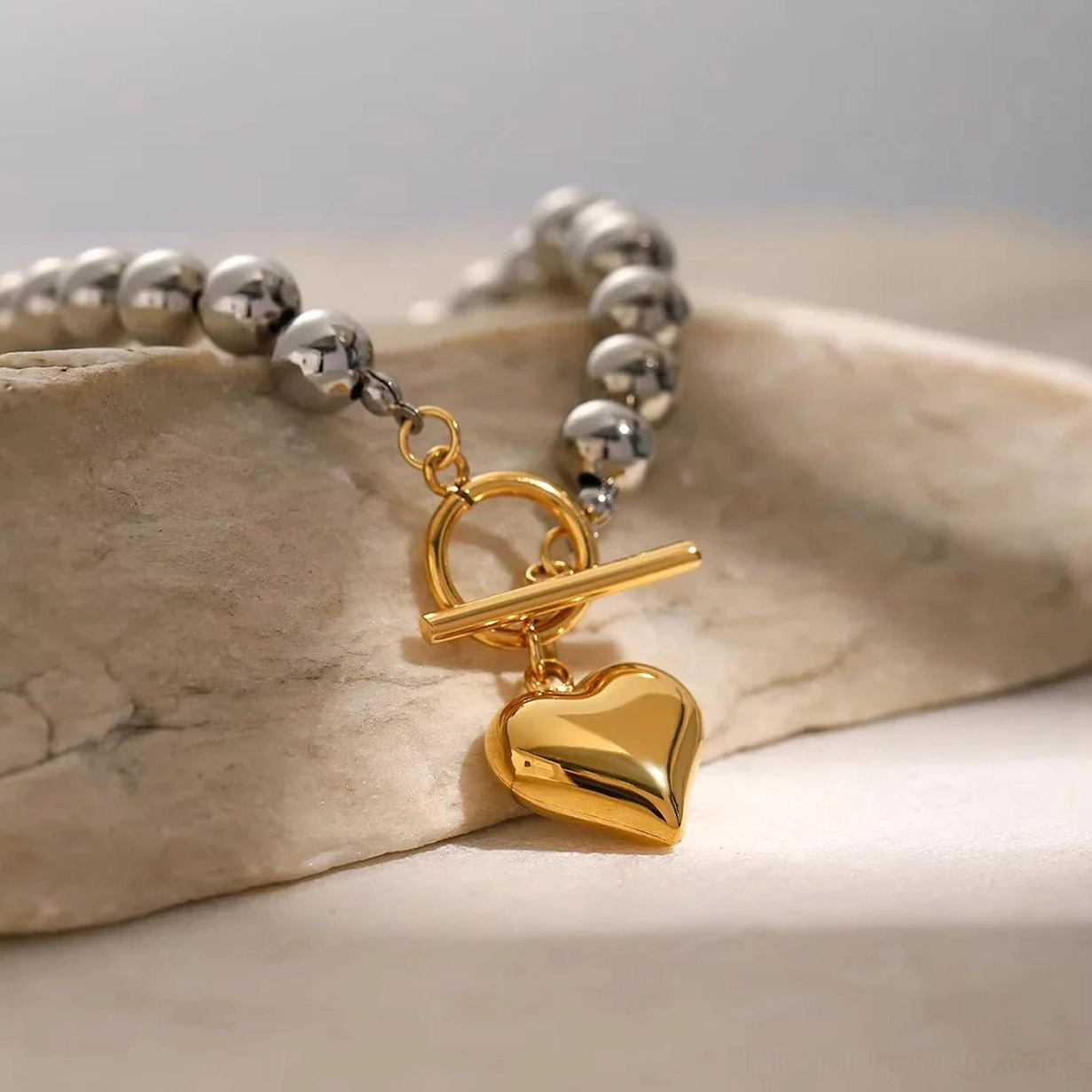 18K gold heart charm beaded bracelet side view detail shot stone background chunky beads