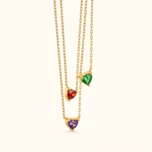 Multi-color 18K gold heart birthstone necklaces collection - front flat lay showing January garnet, emerald green, and purple amethyst pendants on delicate gold chains