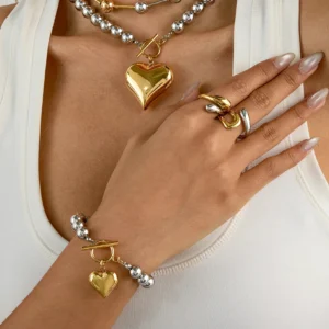 18K gold heart bracelet styled on model with layered necklaces matching jewelry set worn