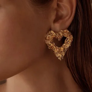 Gold heart stud earrings worn on earlobe close-up view showcasing comfortable fit and wavy textured surface on model