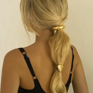 Blonde woman wearing 18k gold heart hair clip in elegant ponytail hairstyle, showcasing polished gold finish and romantic styling