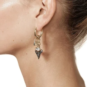 Gold heart charm dangle earring close-up worn on ear side profile elegant jewelry design