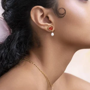 Woman wearing 18K gold heart pearl earrings side angle close-up on earlobe with dark curly hair and gold necklace modeling realistic wear