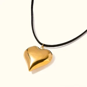 18K gold heart pendant necklace with polished solid gold heart charm and black suede cord, front view on plain background