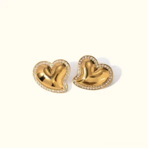 18K gold heart stud earrings with cubic zirconia front flat lay on off-white background, polished gold finish puffy design