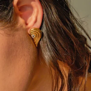 18K gold heart wing earrings worn on ear - side close-up view showing earring on model