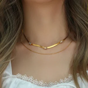 Layered 18K gold herringbone necklace worn on model with brown wavy hair white lace top