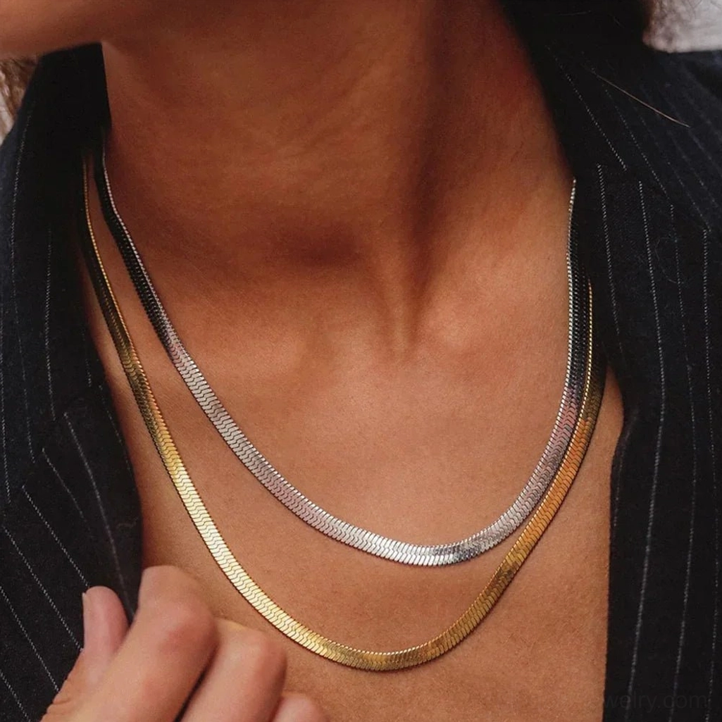Two-tone herringbone necklace set featuring gold and silver chains worn together on model with professional styling