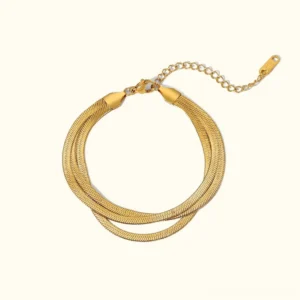 18K gold herringbone triple layered bracelet flatlay with three pre-stacked chains on plain background