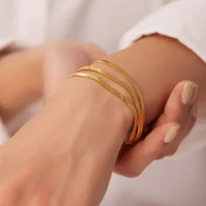 Three-layer 18K gold herringbone bracelet worn on female wrist with adjustable extension clasp close-up