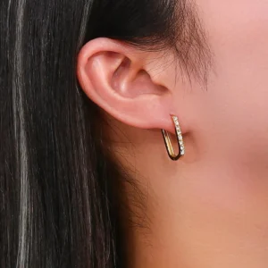 18K gold crystal hoop earrings worn on model ear, close-up side view showing polished gold and sparkling crystal detail, professional jewelry photography