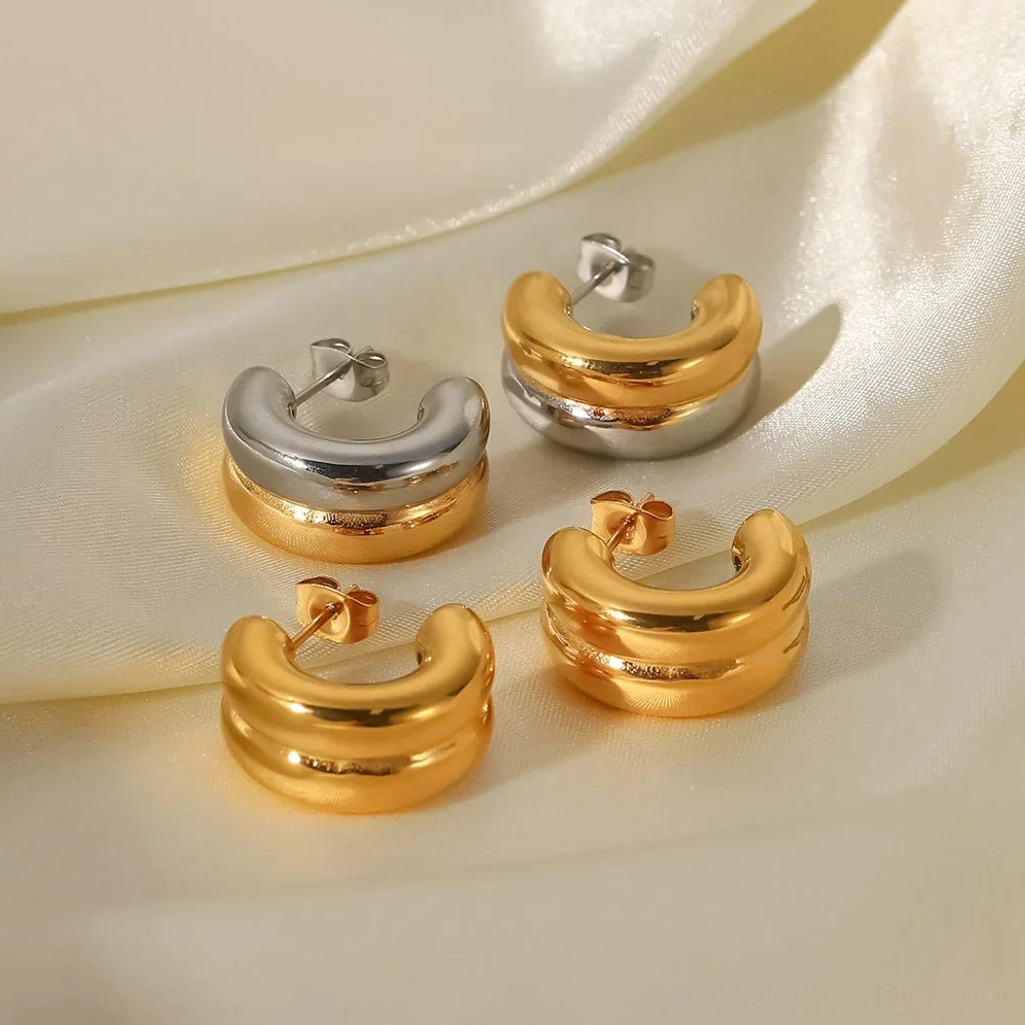 Four pairs of 18K gold chunky hoop earrings in solid gold and two-tone options, flat lay arrangement on ivory satin