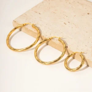 Mixed sizes 18K gold twisted ribbed hoop earrings with travertine stone styling on neutral background
