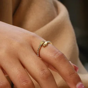 18K gold hug ring worn on female hand side view - adjustable ring with clear decorative details and pink nail art