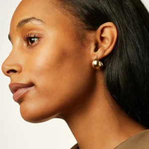 18K gold huggie earrings worn on ear profile close-up shiny solid gold hoop