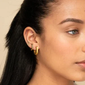 18k gold huggie hoop earrings mixed collection worn on model showing oval hoops and diamond studs close-up side view