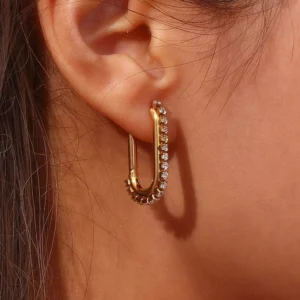 Close-up side view of 18K gold cubic zirconia huggie earrings worn on ear showing pavé CZ sparkle and details