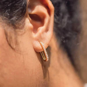 Woman wearing 18K gold huggie hoop earrings close-up rear view, secure fit on earlobe with sparkling cubic zirconia accents