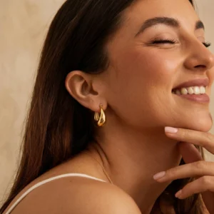 Woman wearing polished 18K gold crescent hoop earrings close-up facial profile view highlighting elegant teardrop shape on earlobe