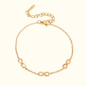 18K gold infinity charm bracelet with multiple infinity symbols on delicate cable chain, flat lay on plain white background, polished gold finish