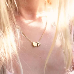 Personalized initial letter A heart gold necklace worn on model collarbone dainty pendant