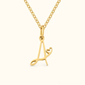 18K gold cursive A initial letter necklace with small heart charm on delicate curb chain, front view studio product photography