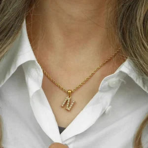 18K gold initial N pearl necklace worn on woman with white collared shirt close-up