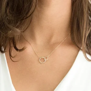 Close-up view of 18K gold double hoop necklace worn on female model's neck with white top