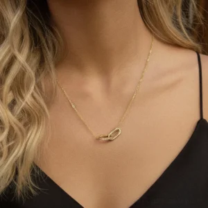 Dainty interlocking pendant necklace worn on blonde model neck with black camisole styling close-up
