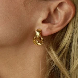 Gold twisted layered hoop earrings worn on ear close-up side profile blonde woman model